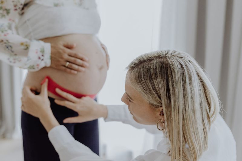 Frauenärztin Dr. med. Rieke Hermann klebt ein Tape auf schwangeren Bauch.